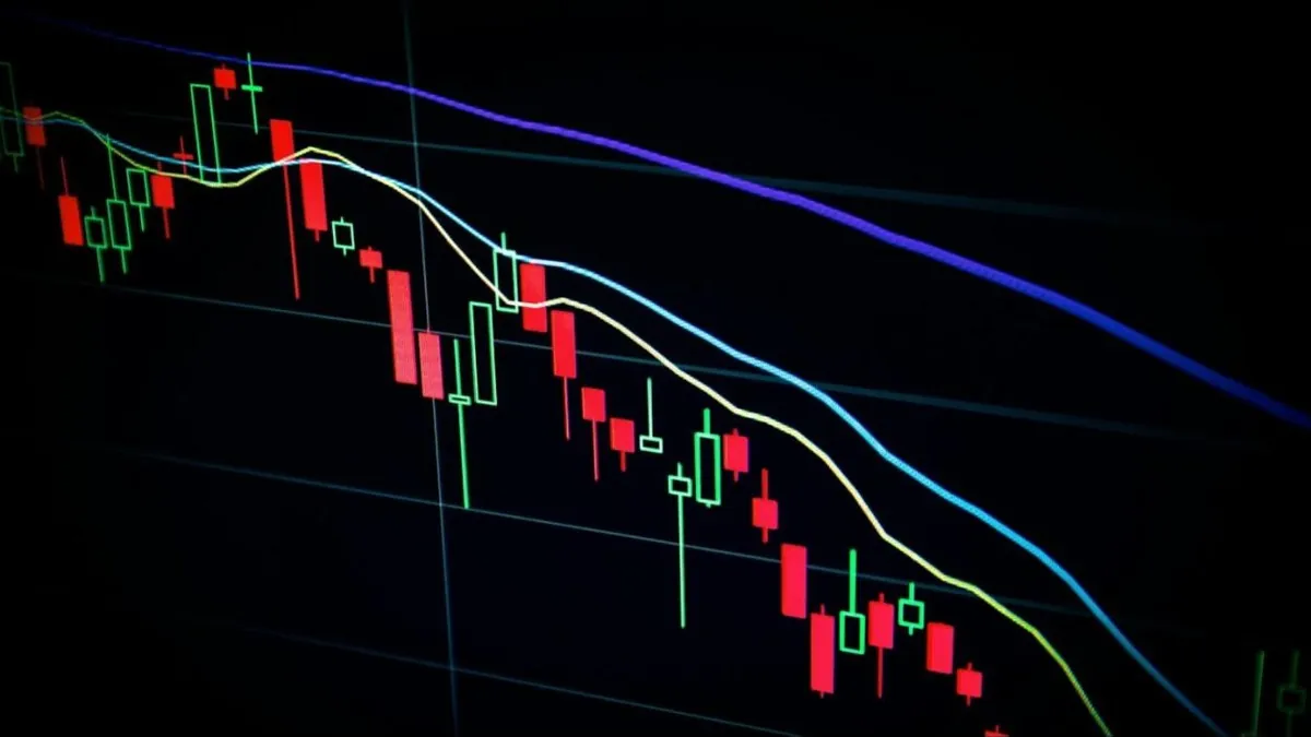 Gráfico de velas de cotação em tela de computador, com tendência de queda