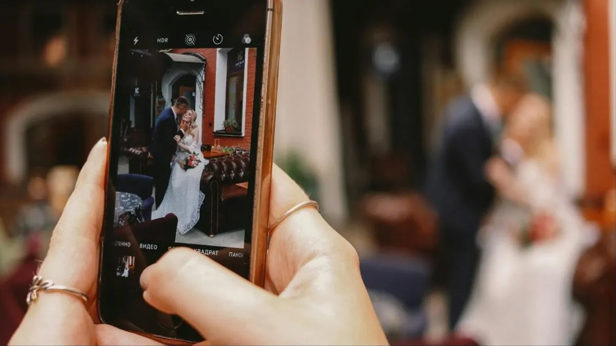 Convidada grava os noivos com o celular durante o casamento